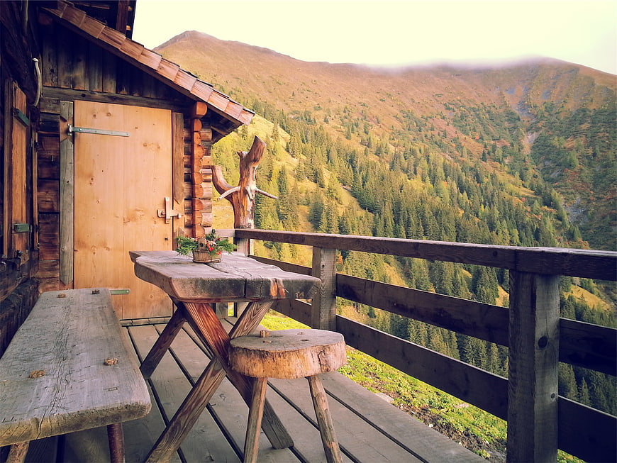Rustic wooden cabin balcony with mountain forest view