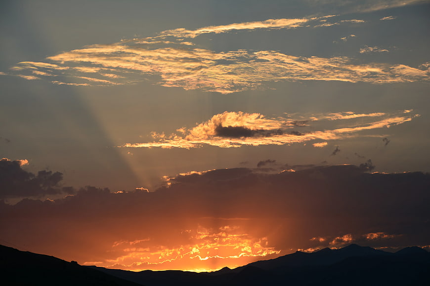 Dramatic sunset with sun rays over mountain silhouette