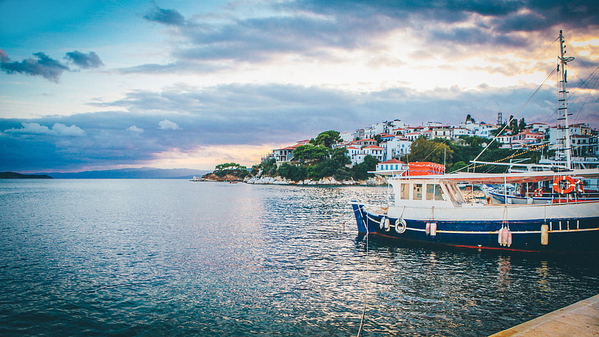 Boat Docked in Harbor with Coastal Town at Sunset