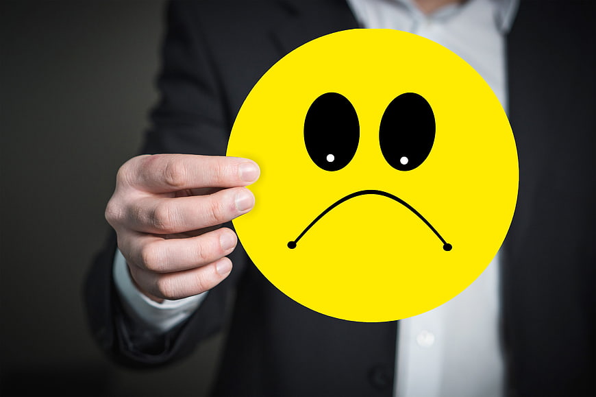 Businessman holding yellow sad face emoji sign