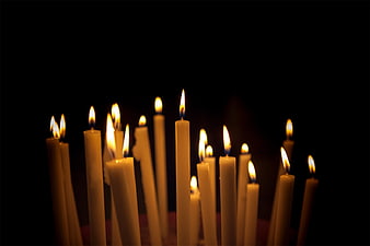 Lit white candles with flickering flames on black background