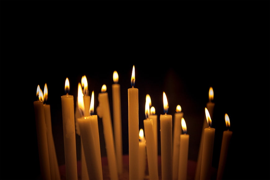 Lit white candles with flickering flames on black background