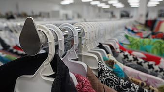 Close-up of white plastic hangers on a metal clothing rack in a retail store