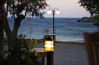 Cozy seaside cafe terrace at dusk with warm lanterns