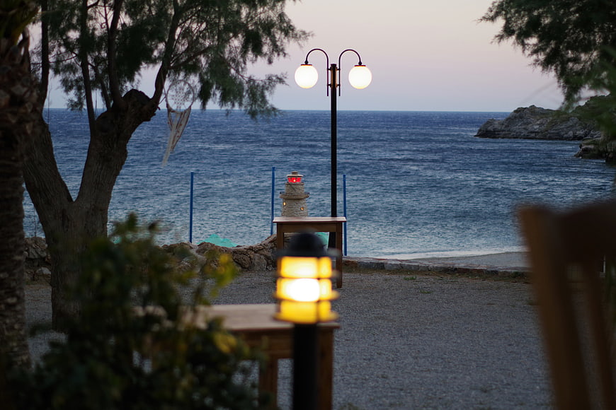 Cozy seaside cafe terrace at dusk with warm lanterns