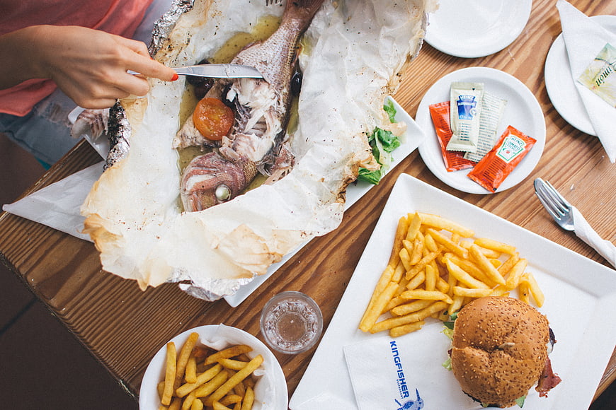 Top view of grilled whole fish and burger meal
