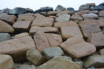 Stacked granite rocks on sandy beach with overcast sky
