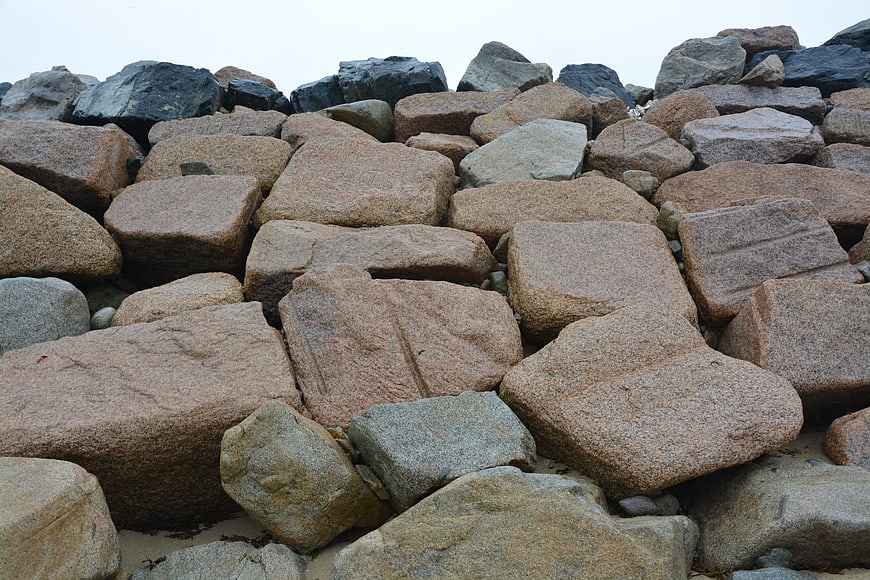Stacked granite rocks on sandy beach with overcast sky