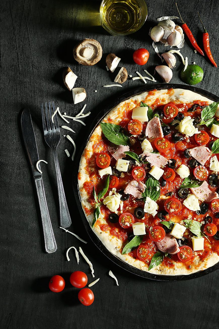 Fresh homemade pizza with toppings on dark wooden table