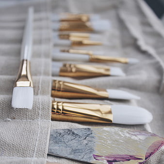Gold and white paintbrushes on canvas with palette knife