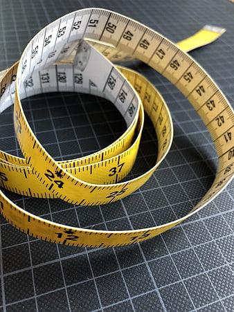 Yellow Measuring Tape Coiled On Black Cutting Mat
