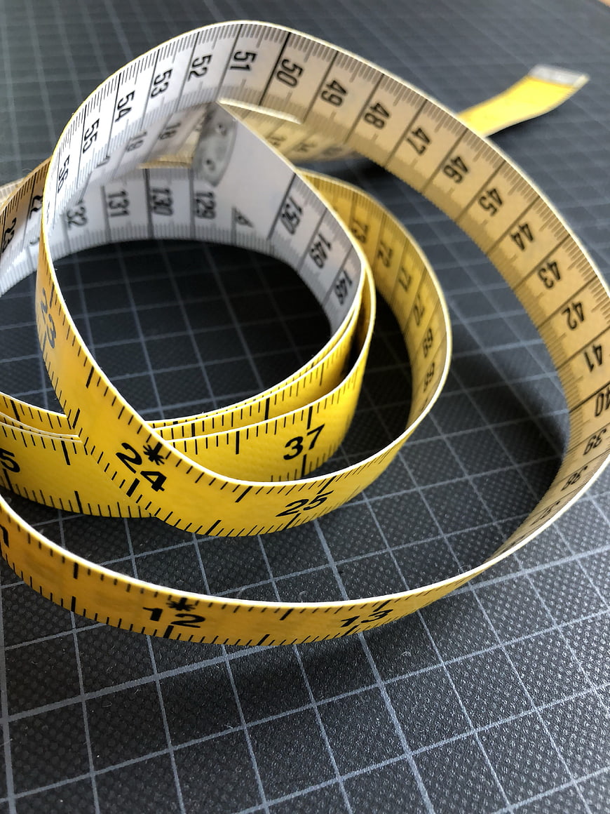 Yellow Measuring Tape Coiled On Black Cutting Mat