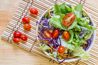 Fresh vegetable salad bowl with tomatoes and cabbage on bamboo mat