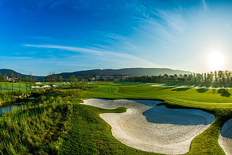Sunlit golf course with sand traps and blue sky