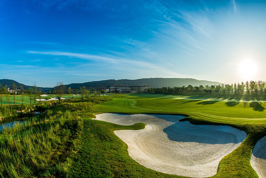Sunlit golf course with sand traps and blue sky