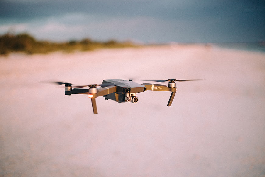 Drone Flying Over Sandy Beach at Sunset