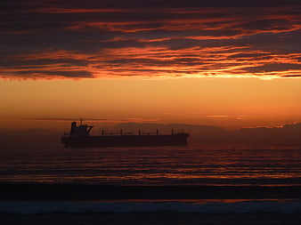 Silhouette of cargo ship on ocean at sunset
