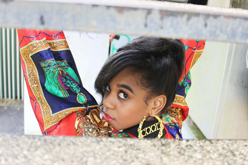 Stylish Woman Peeking Through Urban Gap with Colorful Scarf