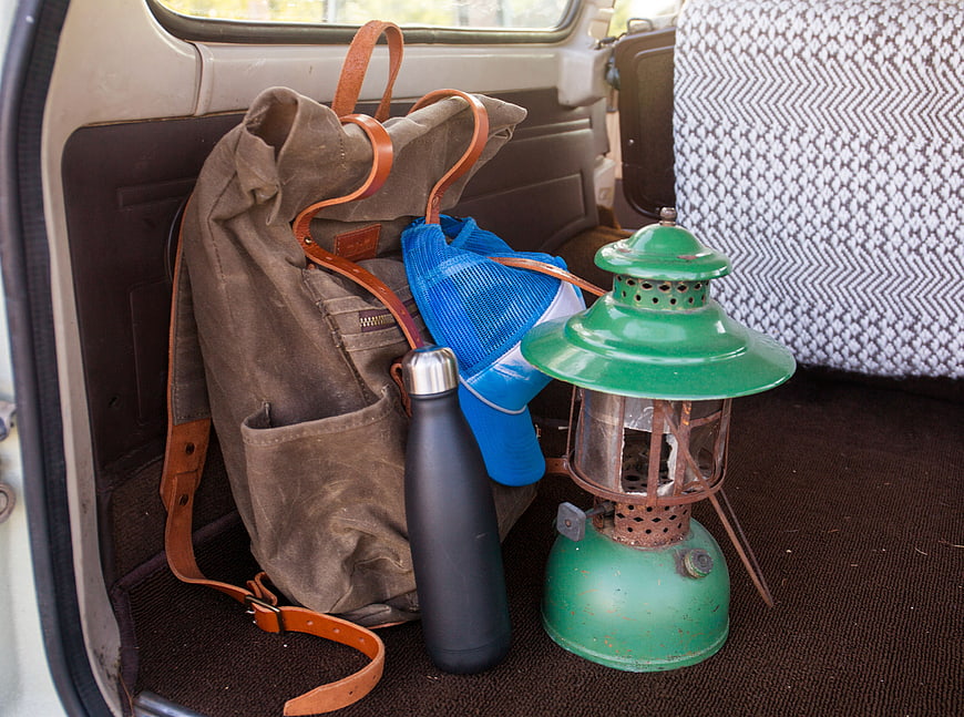Vintage camping gear and backpack in car trunk