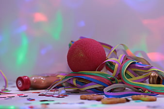Colorful Party Streamers, Red Ball, and Confetti on White Surface
