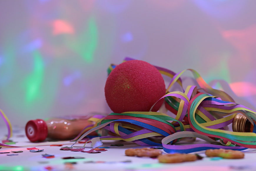 Colorful Party Streamers, Red Ball, and Confetti on White Surface