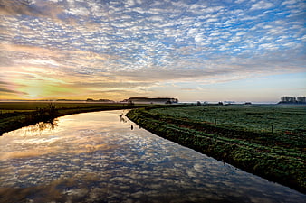 Serene River Sunrise with Cloud Reflections in Frosty Meadow