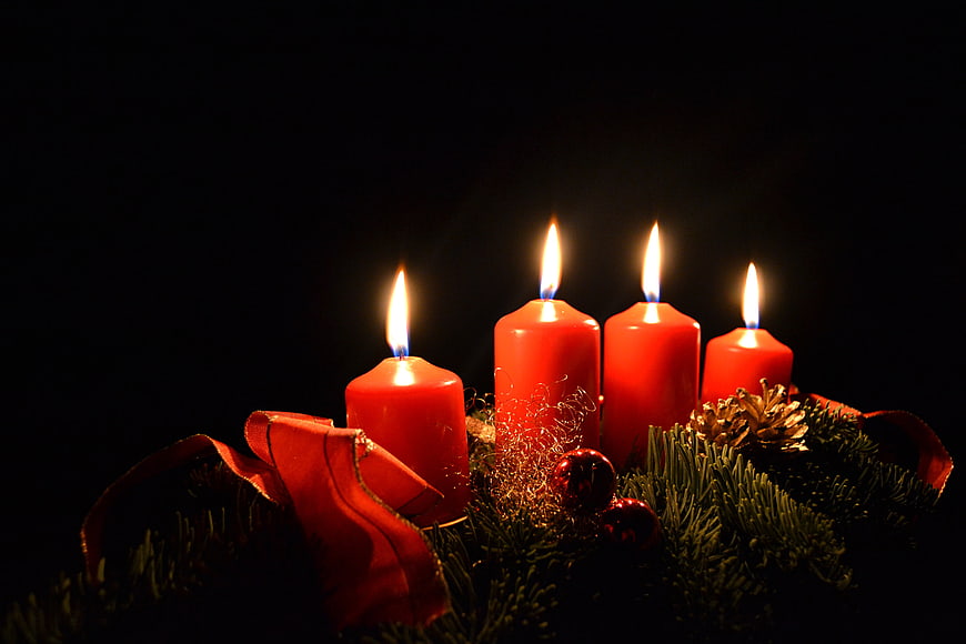 Lit Red Advent Wreath Candles With Pine And Ribbon On Black Background