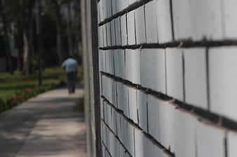 Close-up of white tiled wall with blurred person walking away