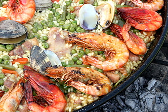 Close-up of traditional seafood paella cooking on charcoal