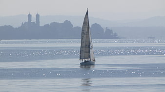Sailboat Sailing on Lake Constance with Distant Castle Silhouette