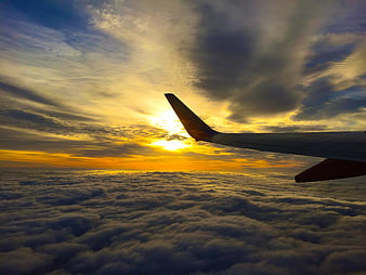 Airplane Wing Over Clouds at Golden Sunset