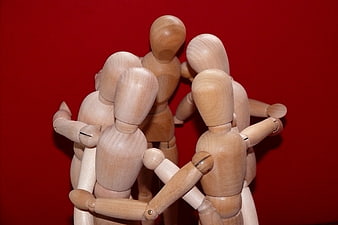 Wooden Mannequins Huddled Together on Red Background