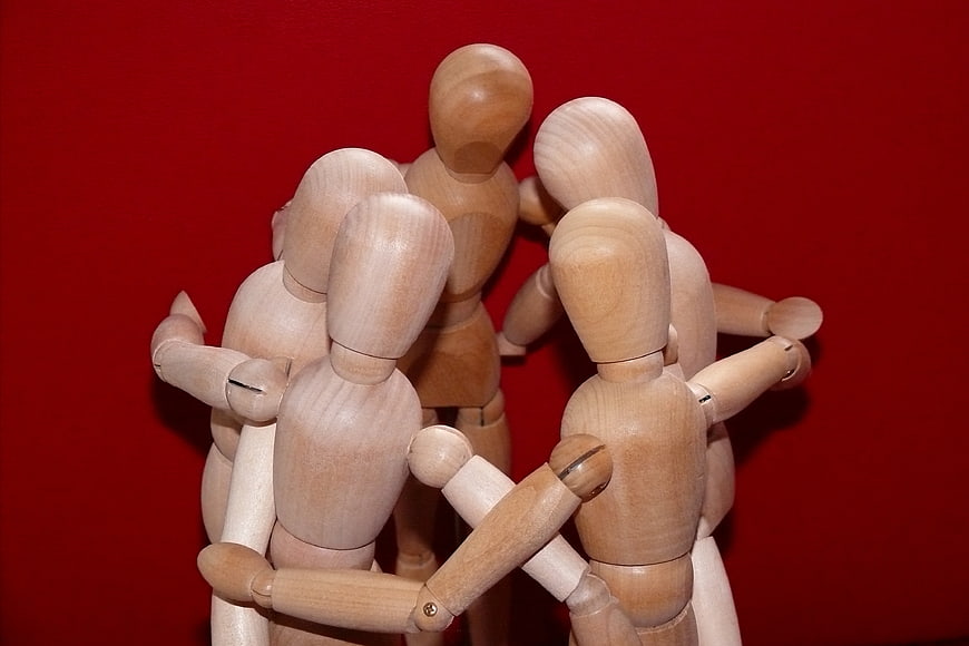 Wooden Mannequins Huddled Together on Red Background