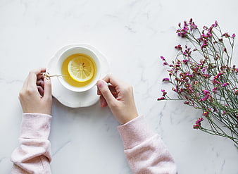 Top view of hands holding lemon tea cup with flowers