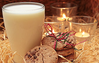 Glass of milk and chocolate chip cookies with candles