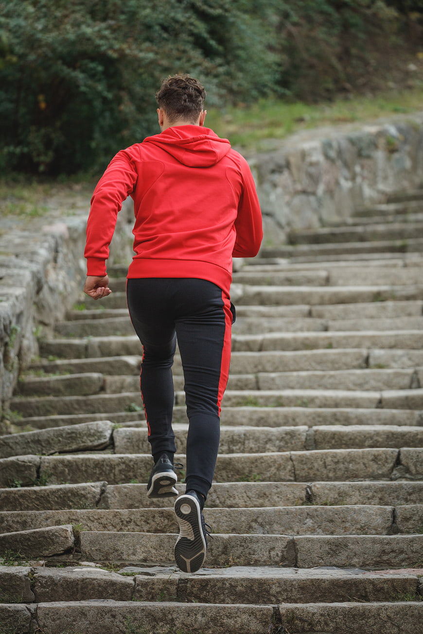 Man in Red Hoodie Running Up Stone Stairs Outdoors