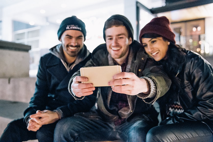Happy friends taking selfie with smartphone outdoors