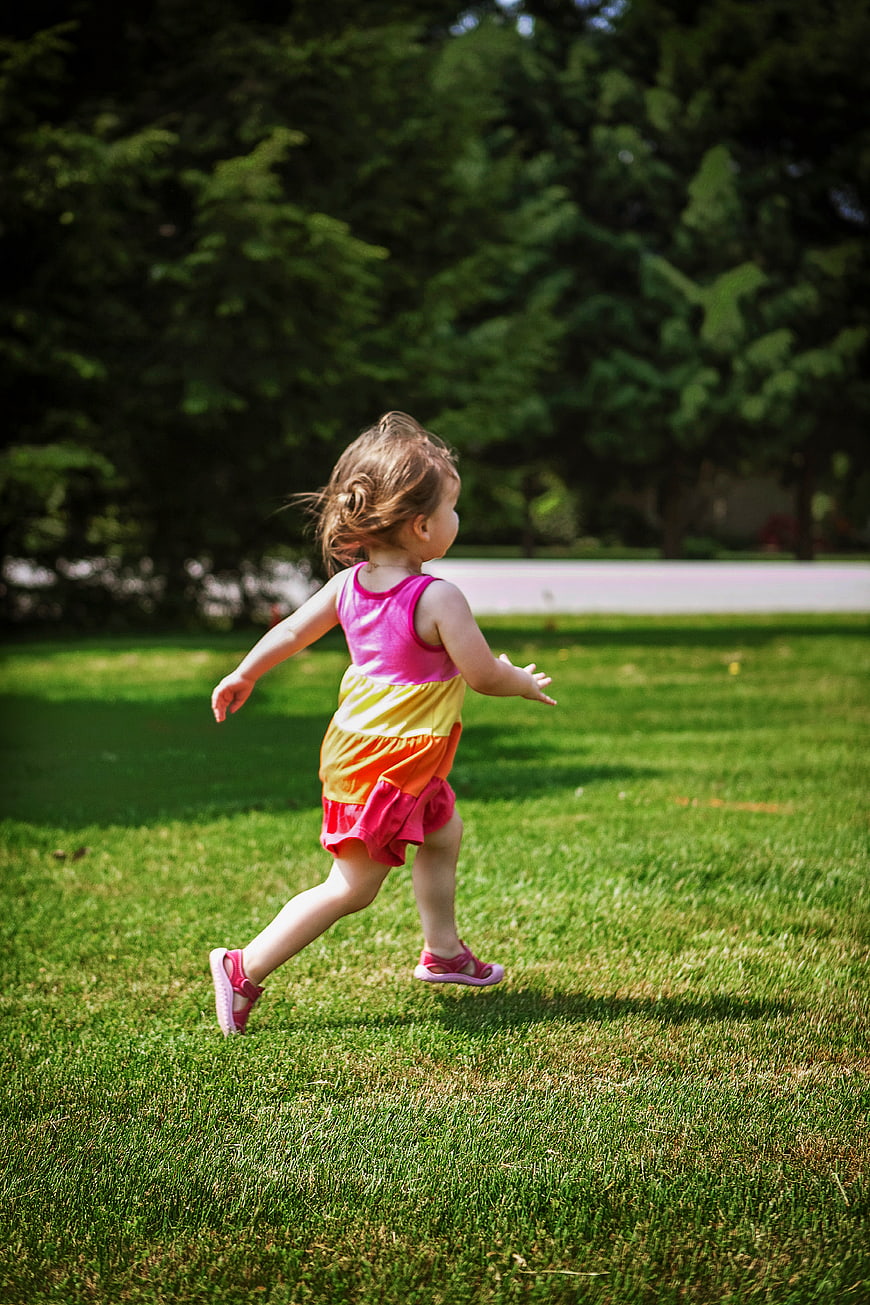 Toddler Girl Running on Green Grass in Park