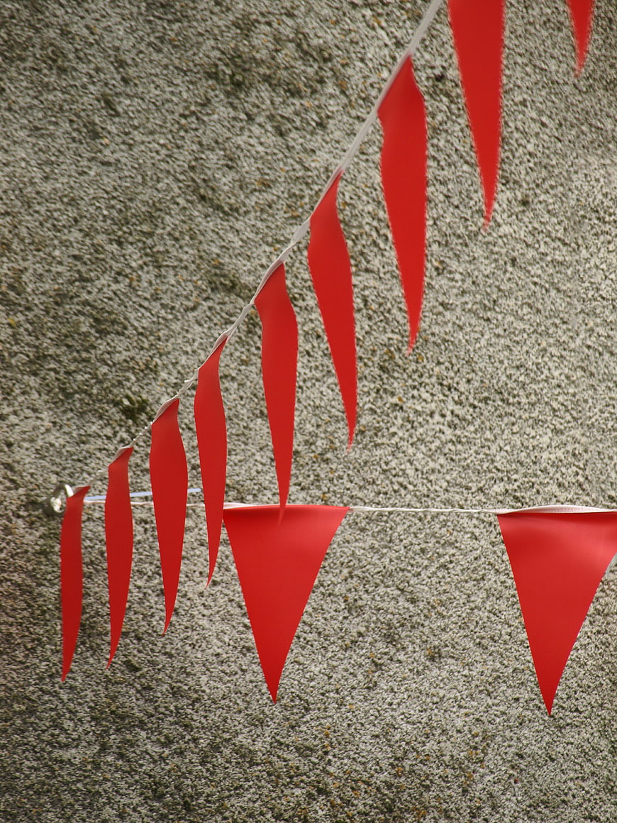 Red triangular bunting flags hanging against a textured wall
