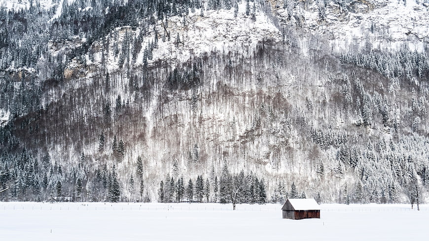 Solitary wooden cabin in snowy mountain valley winter landscape