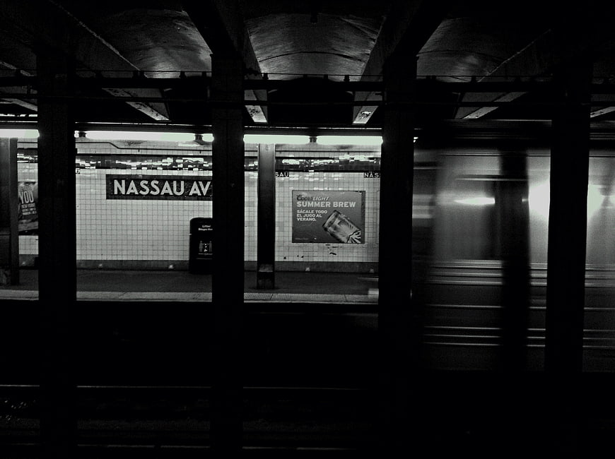 Black and white photo of Nassau Avenue subway station with moving train