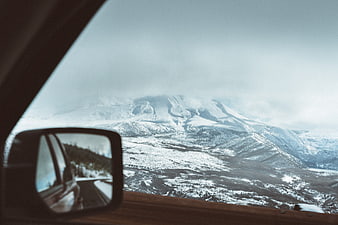 Snowy mountain landscape view from car side mirror