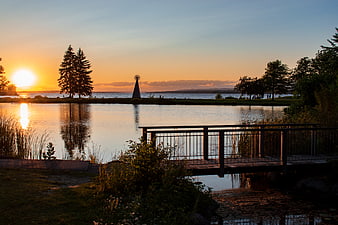 Serene Sunset Over Lake with Wooden Bridge and Sculpture