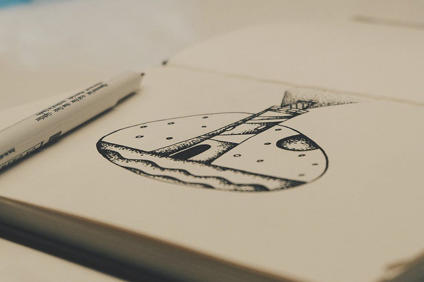 Hand-drawn guitar sketch in notebook with pen