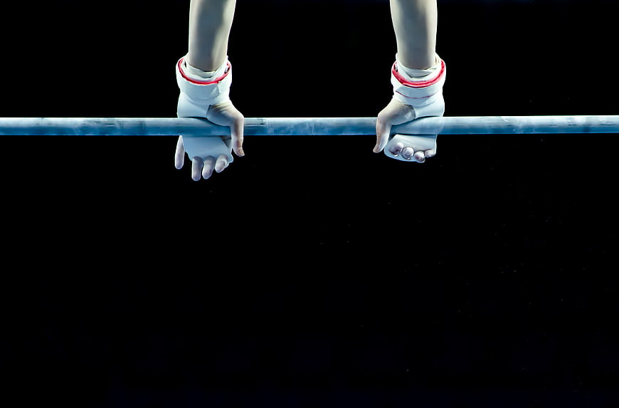 Gymnast Hands Gripping Uneven Bars on Black Background