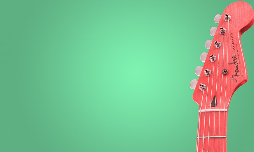 Red Fender Stratocaster Guitar Headstock on Green Background