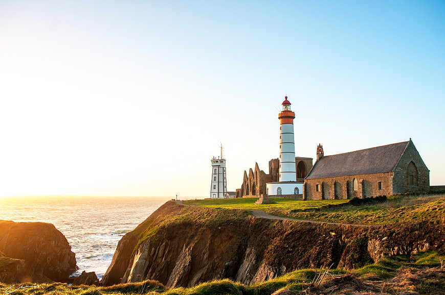 Lighthouse and Ruins on Coastal Cliff at Sunrise