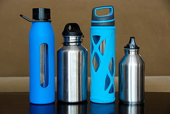 Four reusable stainless steel and blue water bottles on a table