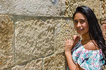 Smiling Teenage Girl with Braces Leaning Against Stone Wall