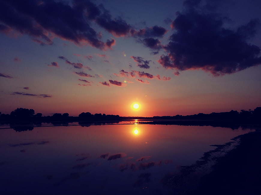 Serene Sunset Over Calm Lake with Cloud Reflections